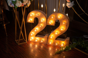 Happy 22 years old celebration. Numbers 22 carved from wood with light. Interior decoration for a birthday - obrazy, fototapety, plakaty