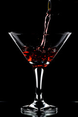 A glass of red wine and a bottle on a black background.