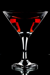A glass of red wine and a bottle on a black background.