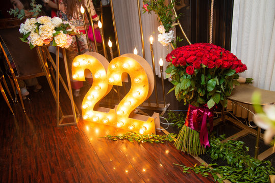 Happy 22 years old celebration. Numbers 22 carved from wood with light and red roses bouquet.