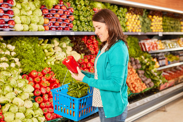 Young woman as a customer is holding a fresh paprika