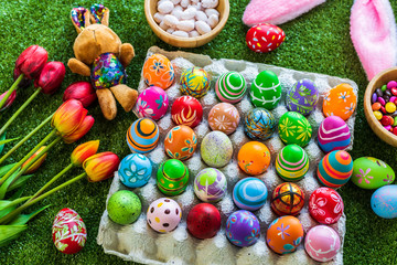Easter holiday concept,Colorful Easter eggs in egg box,basket Easter eggs,candy basket,rabbit doll in green grass background with space.