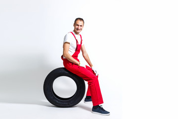 Fototapeta na wymiar working man in full growth holds a tire on a white background
