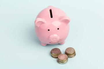 Piggy bank with coin pile on blue background, space for text. Finance, saving money