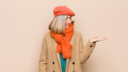 senior or middle age pretty woman feeling happy and smiling casually, looking to an object or...