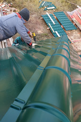 Obraz premium Working with roofing material, screwing the metal tile with a screwdriver.
