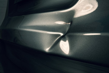 A dent in the body of a silver car in exciting light. - obrazy, fototapety, plakaty