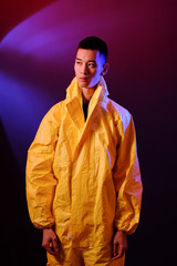 Asian man in a yellow suit of chemical protection on a colored trendy background. Conceptual fashion fashion shooting.