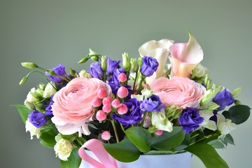 Spring bouquet in the box with pink ribbon. Floral composition with ranunculus, roses and alstroemerias flowers on neutral background