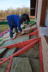 Man installs a thermal insulation layer on the roof - using mineral wool panels.