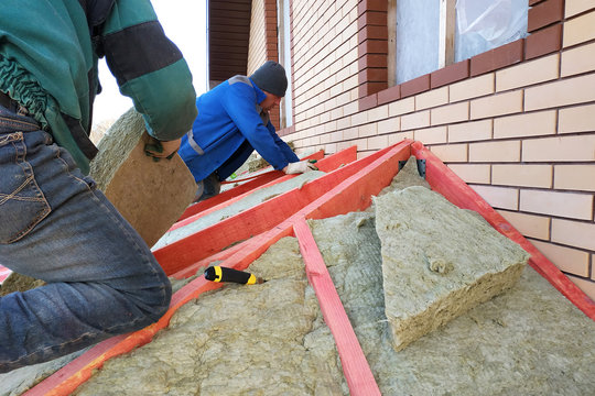 Man installs a thermal insulation layer on the roof - using mineral wool panels.