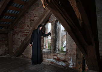 gothic brunette woman standing near the window in attic