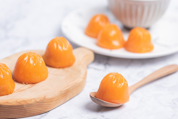 A bun like an orange in a white plate on the table