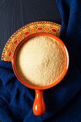 Food concept organic raw couscous in orange bowl on blask slate stone board with copy space © TYSB