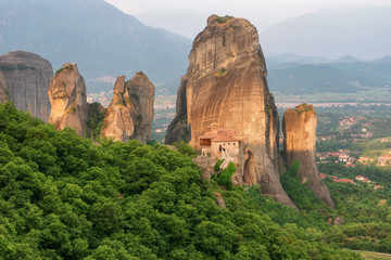 Fototapeta na wymiar Magnificent spring landscape.Orthodox Monastery of Rousanou (St. Barbara), immense monolithic pillar, green foliage at the background of stone wall in Meteora, Pindos Mountains, Thessaly, Greece.