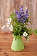 gardening, plants and organic concept - bunch of herbs and flowers in green jug on table