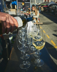 Serving a bottle of white wine in a glass on the street in Bayonne