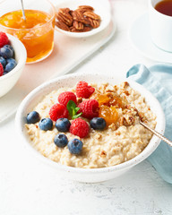 Oatmeal porridge with blueberry, raspberries, side view, close up, vertical, breakfast with berries