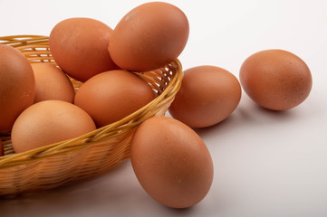 Chicken eggs in a wicker basket and eggs scattered on a white background. Country food. Close up.