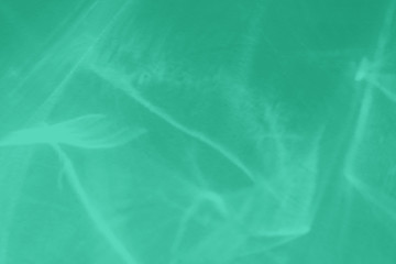 Trendy mint colored abstract background with light and shadows caustic effect. Light passes through a glass. 2020 color trend