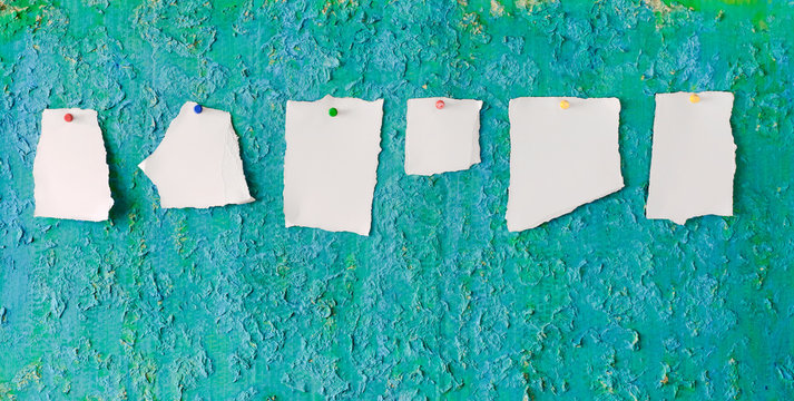 Torn empty leaflets,slips of paper on green grungy notice board,