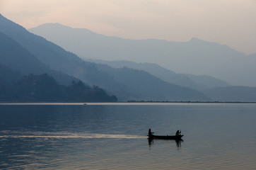 Fototapeta na wymiar Pescadores avanzando por un lago tranquilo sobre una barca de madera