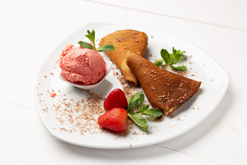 Freshly baked pancakes on a white plate decorated with mint