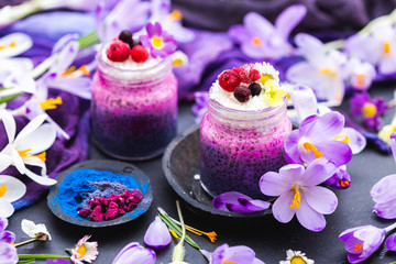 Fototapeta na wymiar Tabletop scene with purple chia smoothies and spring flowers. Spring flat lay with raw vegan food.