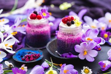 Obraz na płótnie Canvas Tabletop scene with purple chia smoothies and spring flowers. Spring flat lay with raw vegan food.