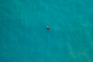 Persona che va con il surf nel mare aperto blu, vista verticale con drone.