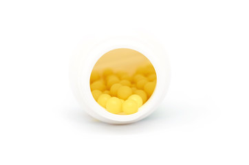 yellow round pills lie in a white jar isolated on white background
