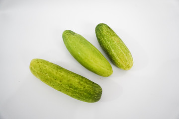 three fresh green cucumbers on a white background