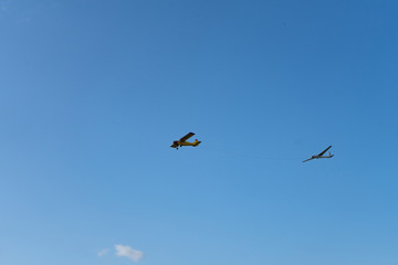 Plane pulling glider. White clouds in background. Self propelled glider in air. Plane dragging the glider.