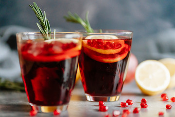 Pomegranate drink in a glass with lemon and rosemary