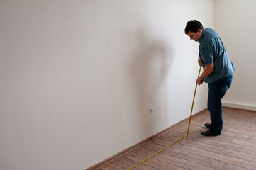 Man measuring white wall. Construction tool