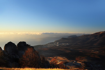 View from the top of the mountains in the early morning on the sea and clouds with fog over the water. The sun rising over the horizon from the water.