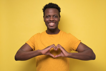 guy cheerfully and making heart gesture over chest, expressing his feelings