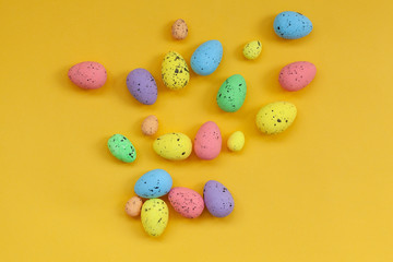 Fototapeta na wymiar Multicolored Eggs with confetti on yellow background background. Easter concept.