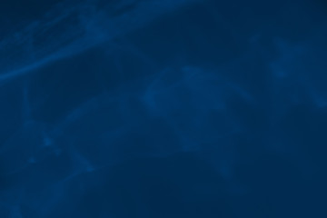 Trendy blue colored low contrast abstract background with light and shadows caustic effect. Light passes through a glass. Water background. 2020 year color trend