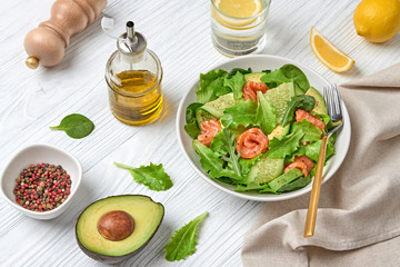 Salmon salad, cucumber, spinach, lollo, lettuce. Home made vegetarian salmon salad. Seafood tasty diet concept. Mix leaves greens with salmon fish in plate on white wood background.