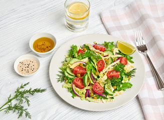 Fresh salad with cherry tomatoes, savoy cabbage, cucumeber on dish. Healthy summer salad vegetarian meal concept. Tasty mixed leaves, tomatoes and mix vegetable salad on white wood