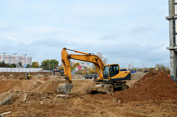 Wheel excavator working at a construction site during laying or replacement of underground storm sewer pipes. Backhoe dig the ground for the foundation, laying storm sewer pipes.
