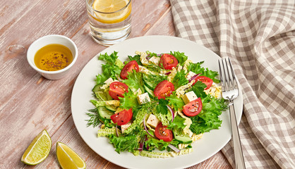 Fresh salad with cherry tomatoes, savoy cabbage, cucumeber on dish. Healthy summer salad vegetarian meal concept. Tasty mixed leaves, tomatoes and mix vegetable salad on wood background