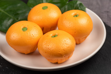 Fototapeta na wymiar Pork dumpling in cartoon style,Pork bun like an orange in a white plate on the indoor dining table