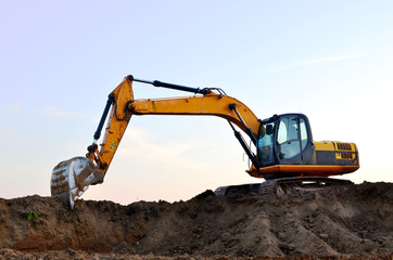 Excavator digs the ground for the foundation and construction of a new building. Road repair, asphalt replacement, renovating a section of a highway, laying or replacement of underground sewer pipes
