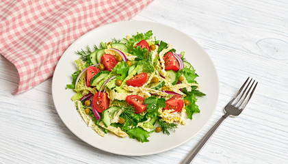 Fresh salad with cherry tomatoes, savoy cabbage, cucumeber on dish. Healthy summer salad vegetarian meal concept. Tasty mixed leaves, tomatoes and mix vegetable salad on white wood