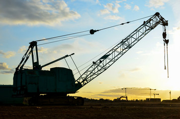 Crawler crane on the construction site. Heavy industrial machinery on the background sunset