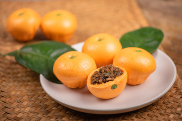 Pork dumpling in cartoon style,Pork bun like an orange in a white plate on the indoor dining table