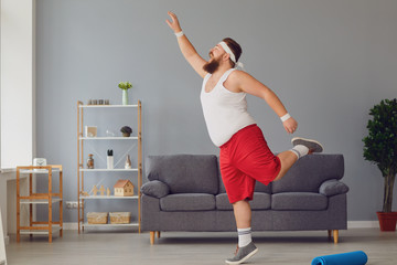 échauffer efficacement Funny red fat man doing exercises while standing at home.