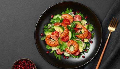 Shrimps salad, avocado, lettuce, cherry tomatoes. Home made vegetarian shrimp salad. Seafood concept. Tasty veg mixed leaves, grilled prawn shrimps in plate on black background.